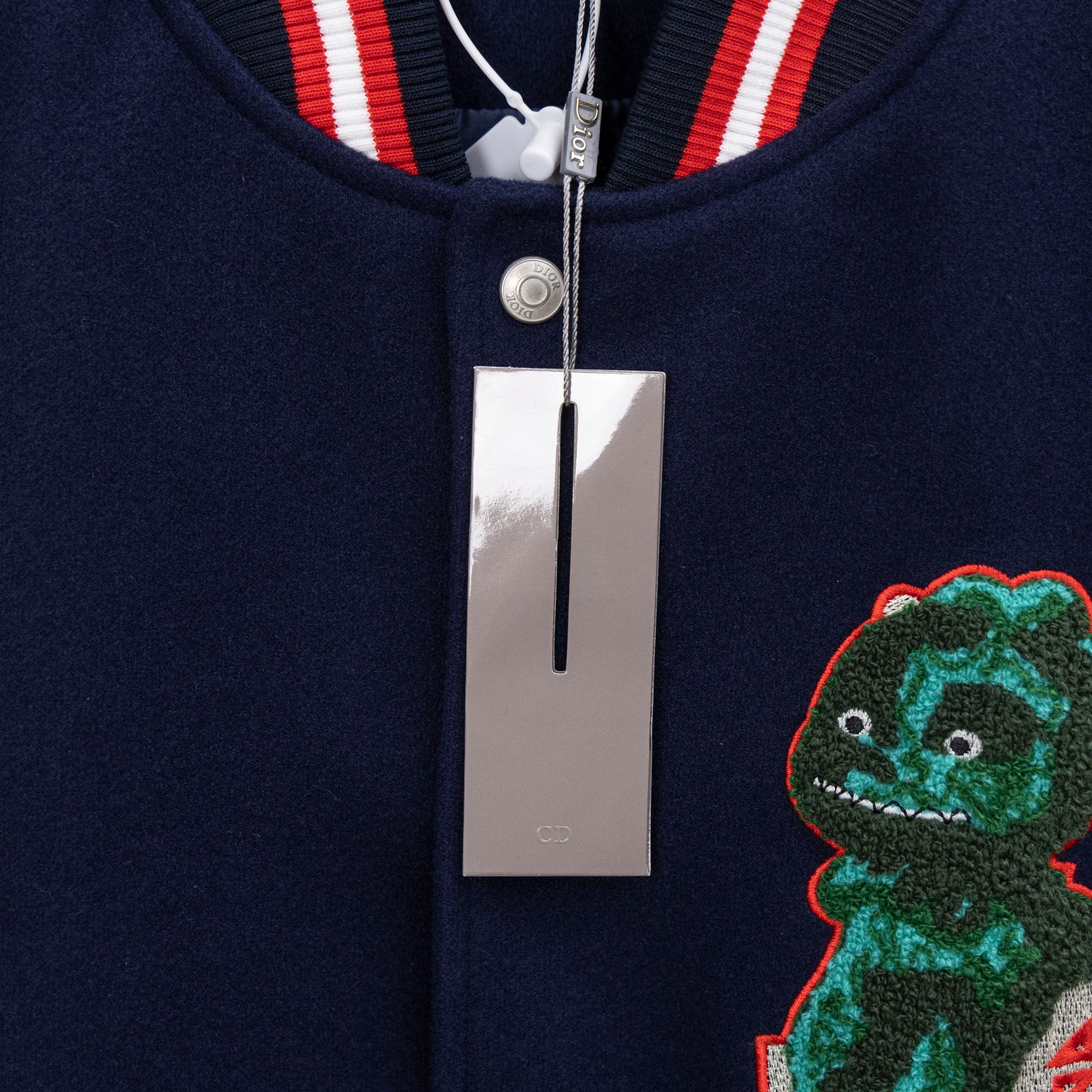 Dark navy jacket neckline with red/white striped ribbing, snap closure, embroidered dinosaur