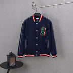Dark navy varsity jacket with snap front, red/white striped cuffs, dinosaur patch