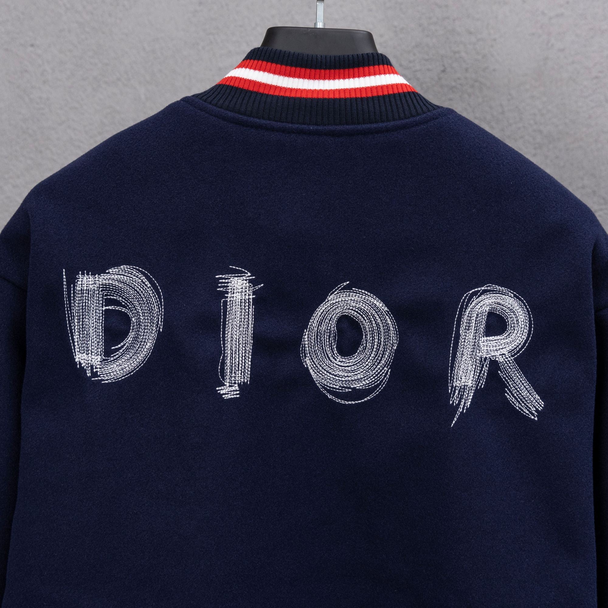 Navy jacket back close-up with DIOR embroidered letters and red/white striped collar