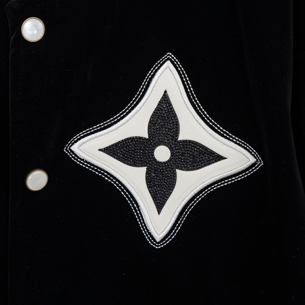 Black jacket with large white-and-black fleur-de-lis patch and snap buttons