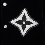 Black jacket with large white-and-black fleur-de-lis patch and snap buttons
