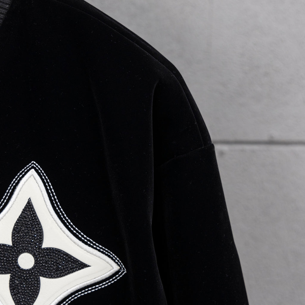 Black jacket sleeve with white-trimmed fleur-de-lis emblem patch
