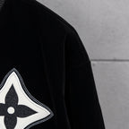 Black jacket sleeve with white-trimmed fleur-de-lis emblem patch