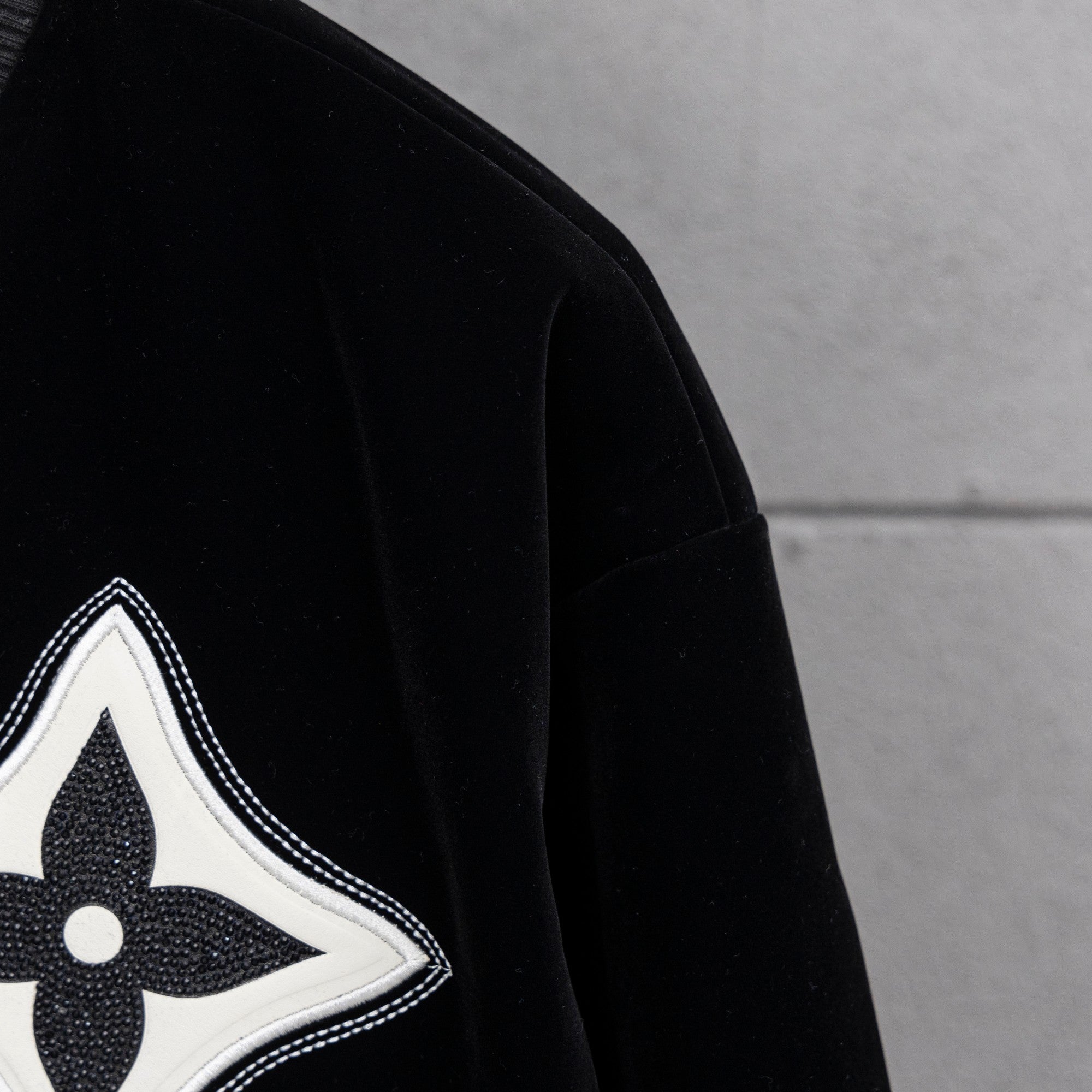 Black jacket sleeve with white-trimmed fleur-de-lis emblem patch