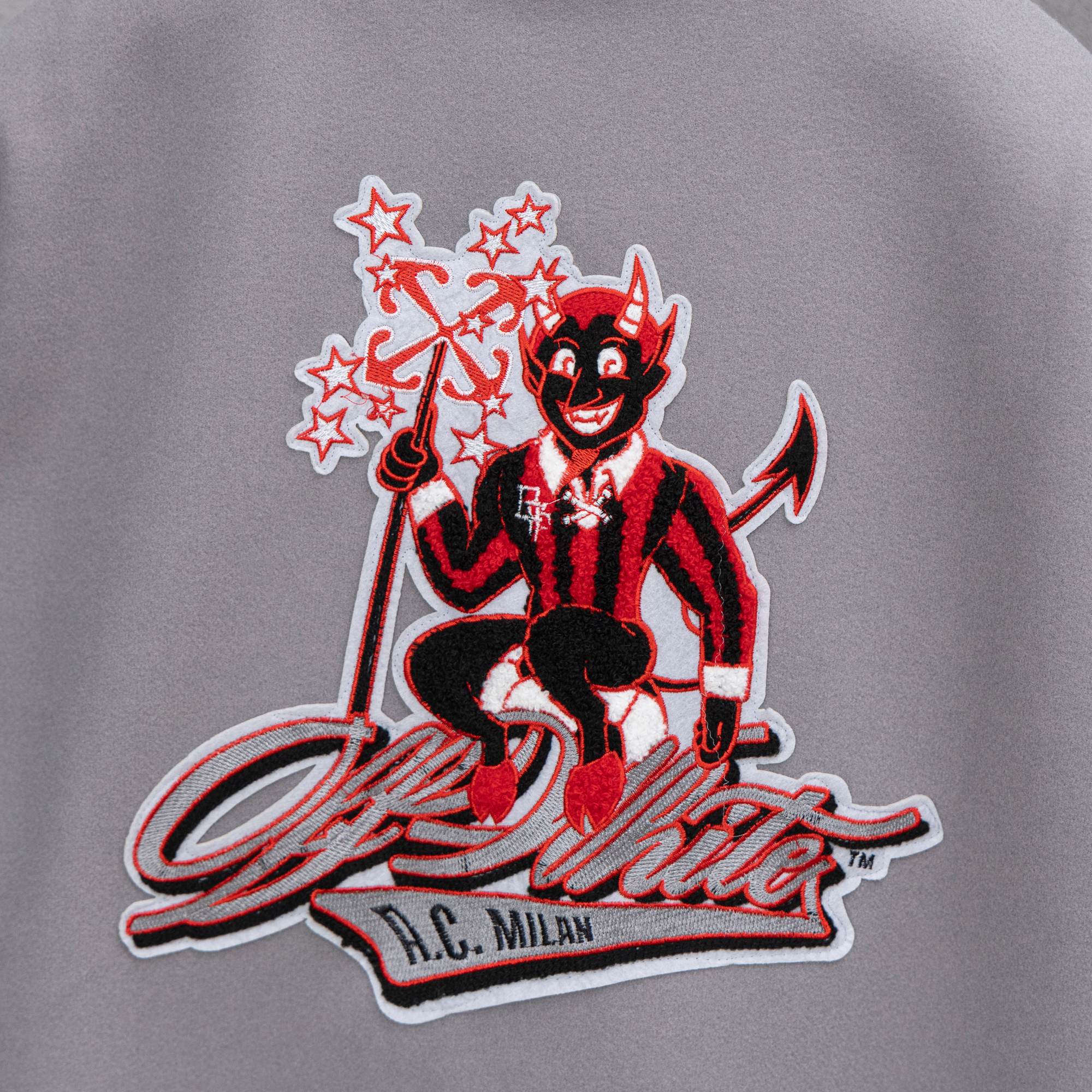 Off White varsity jacket back graphic patch, red cartoon figure on light gray fabric