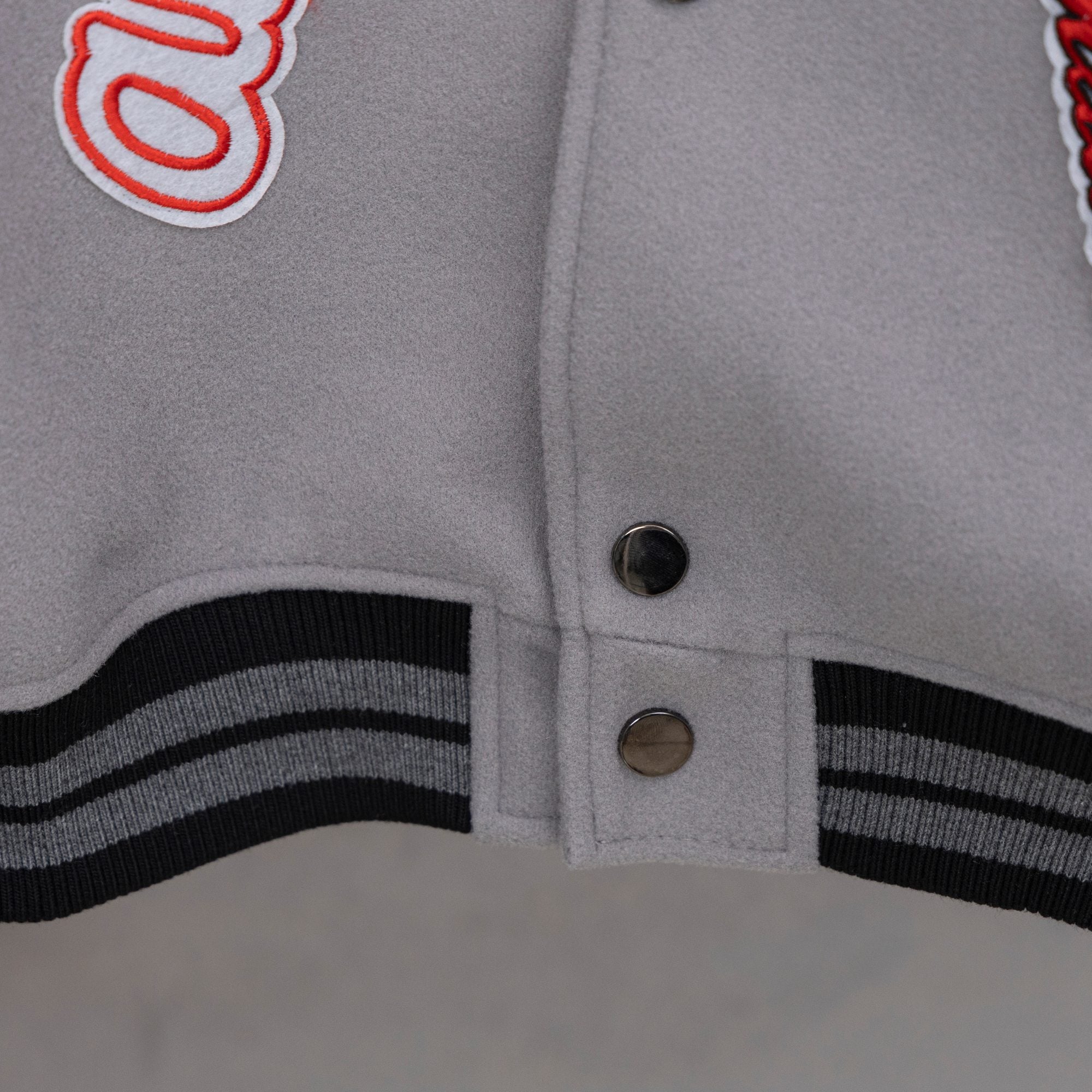 Off White varsity jacket hem cuff with black-and-white striped ribbing and two snap buttons