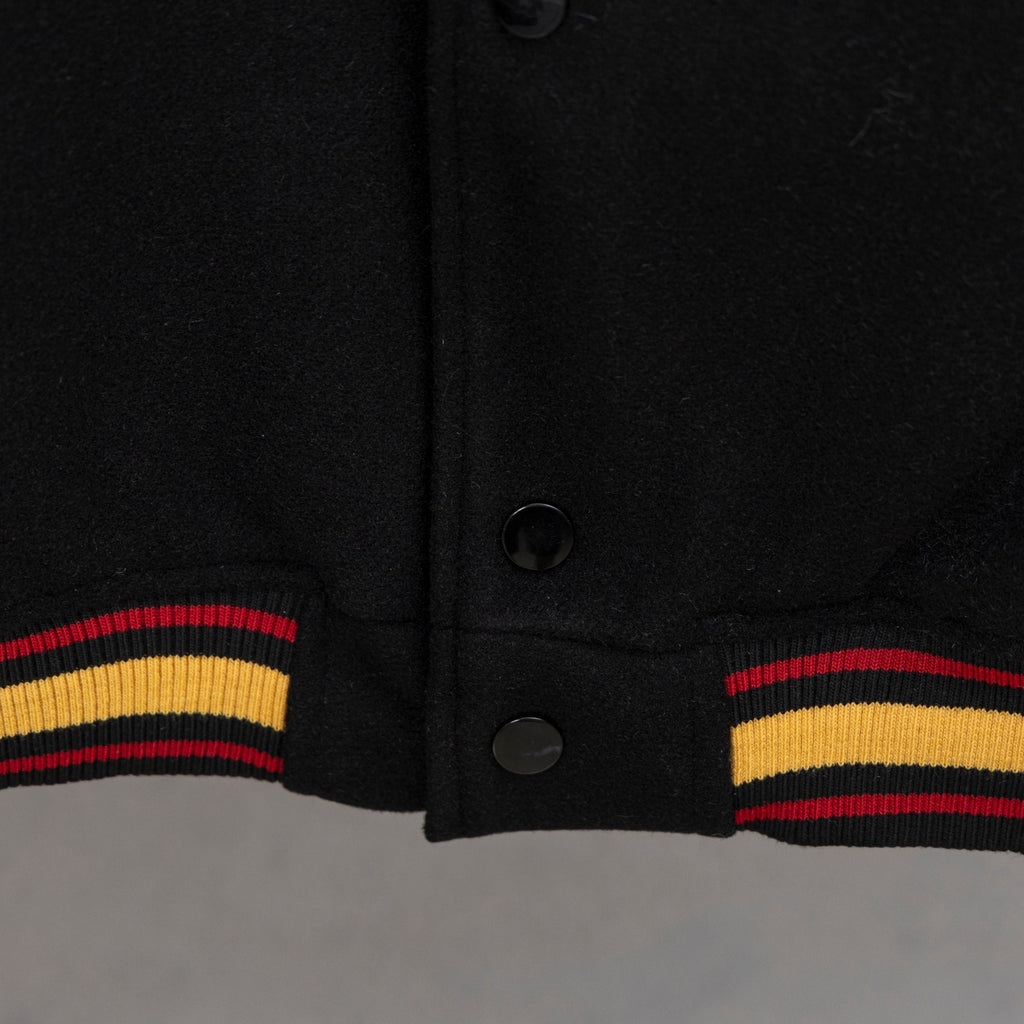 Black varsity jacket hem with snap buttons and ribbed striped cuffs