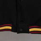 Black varsity jacket hem with snap buttons and ribbed striped cuffs