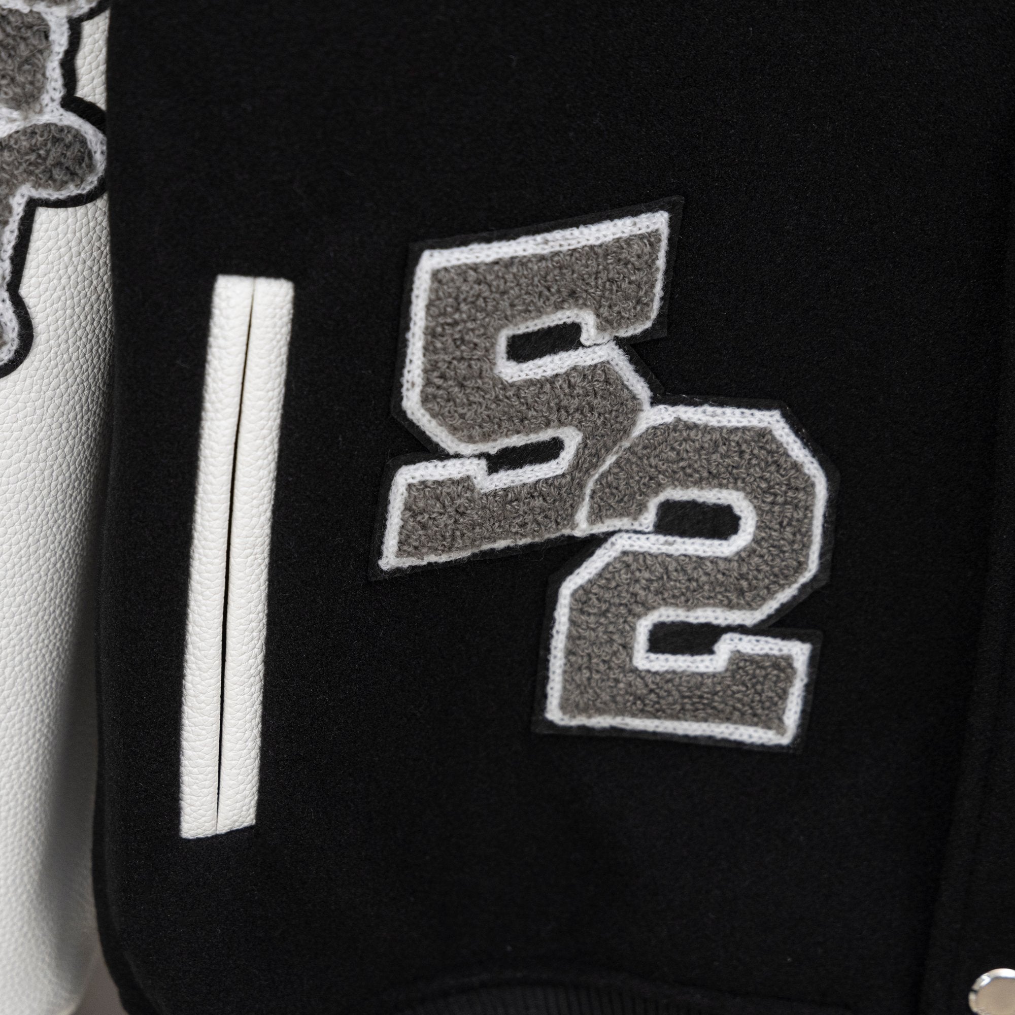 Givenchy jacket front detail with gray stitched numbers and long white sleeve stripe
