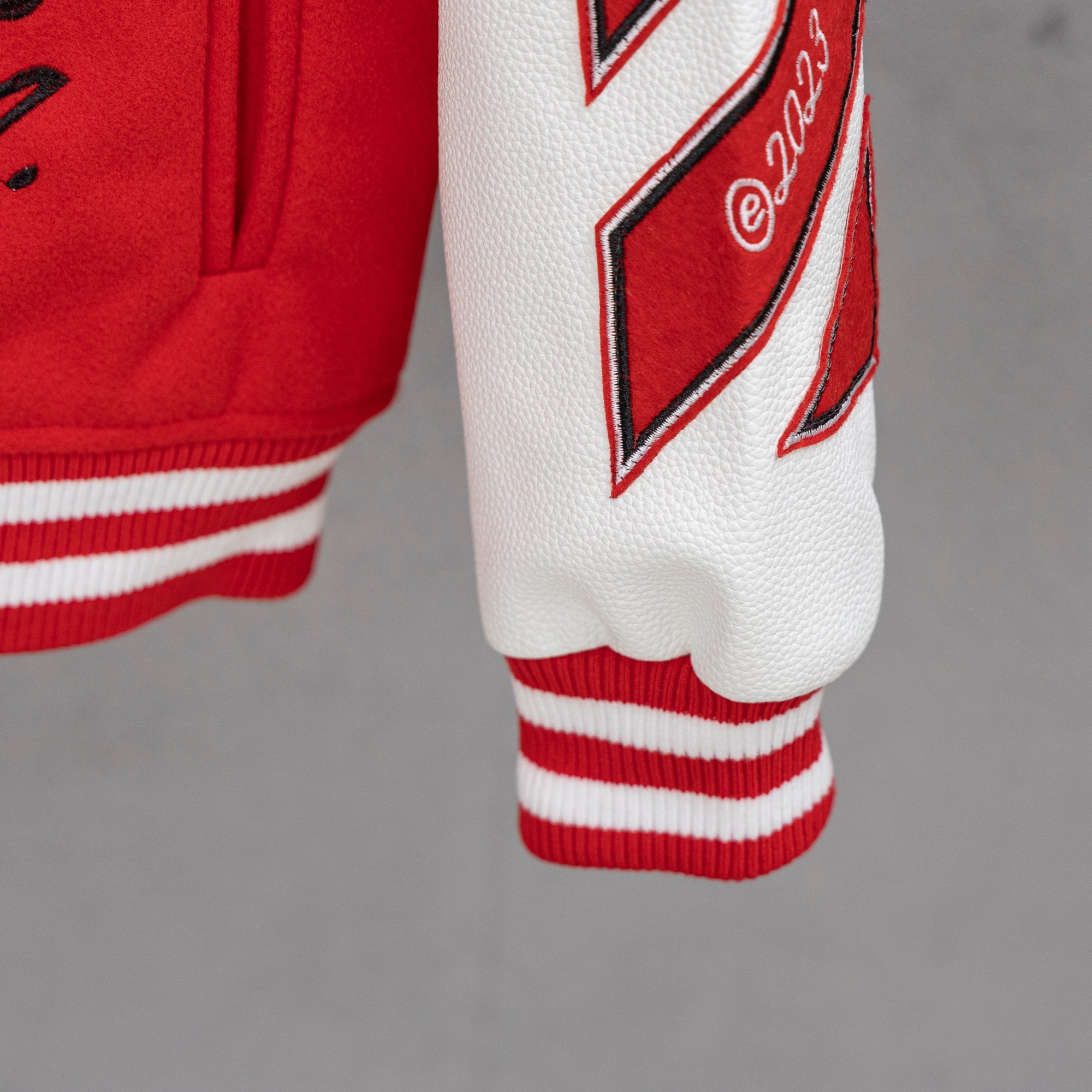 Red sweatshirt cuff with red-and-white striped ribbing and logo patch