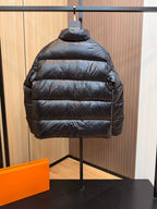 Black puffer jacket back view with horizontal quilted stitching and standing collar.