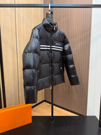 Black hooded puffer jacket with Gucci logo on chest, stripe panel, and zip front.