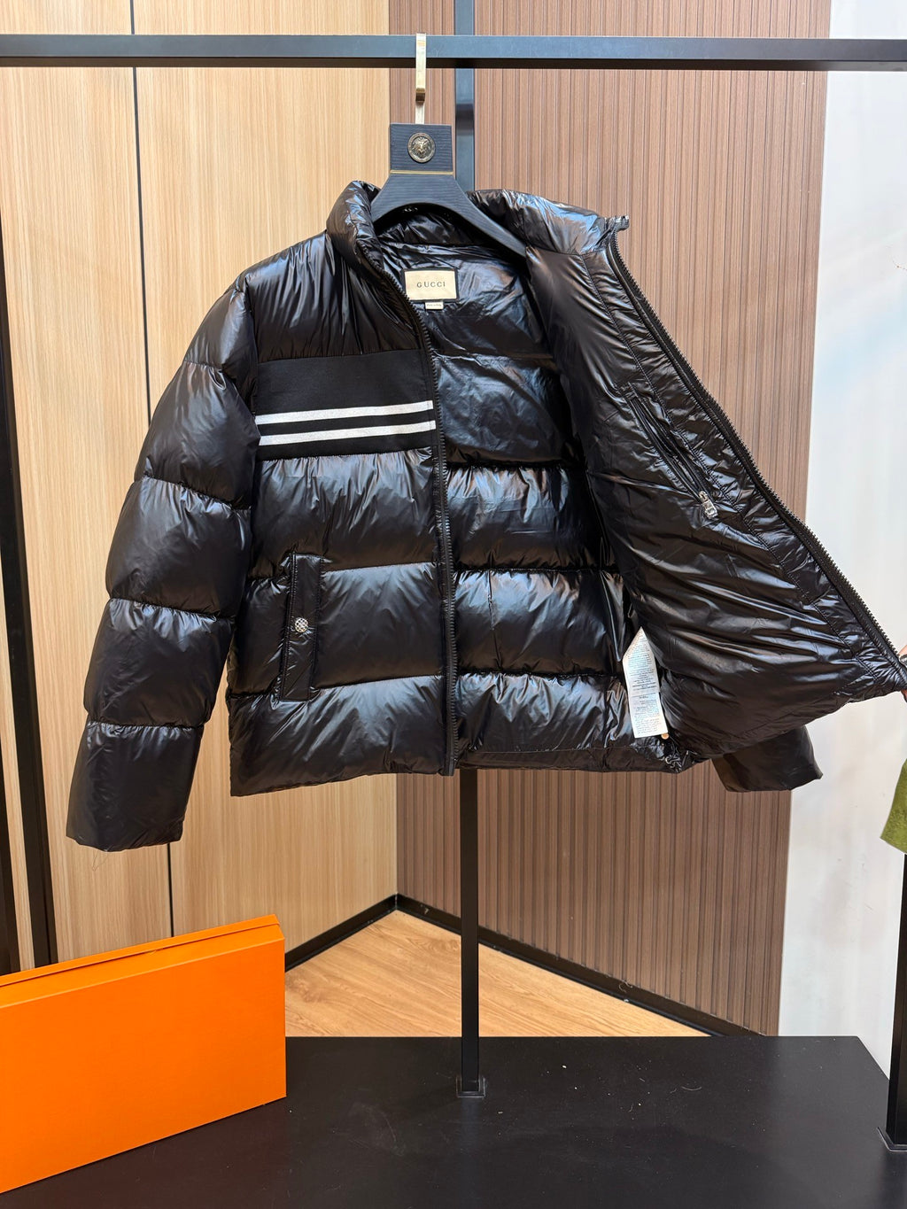 Black puffer jacket partially open at front, showing quilted lining and Gucci logo.