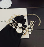 Chanel accessories: gold-tone and white beaded charm bracelets on black cloth
