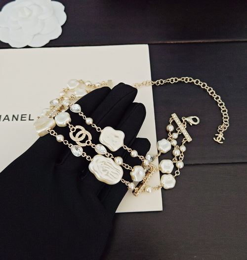Chanel accessories: gold-tone and white beaded charm bracelets on black cloth