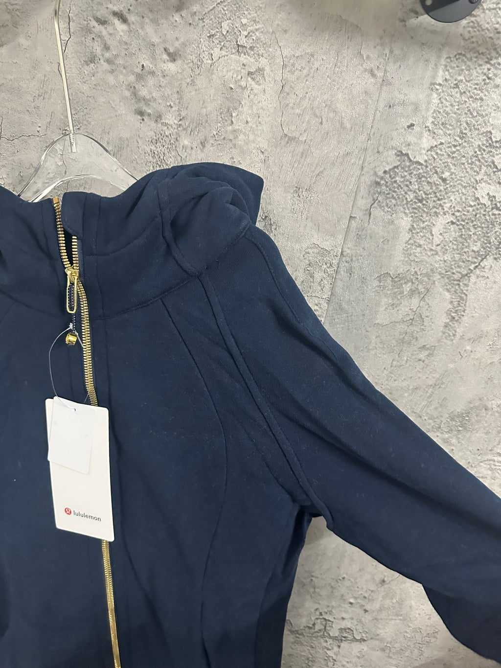 Dark navy zip-up hoodie sleeve and side seam detail with gold zipper trim
