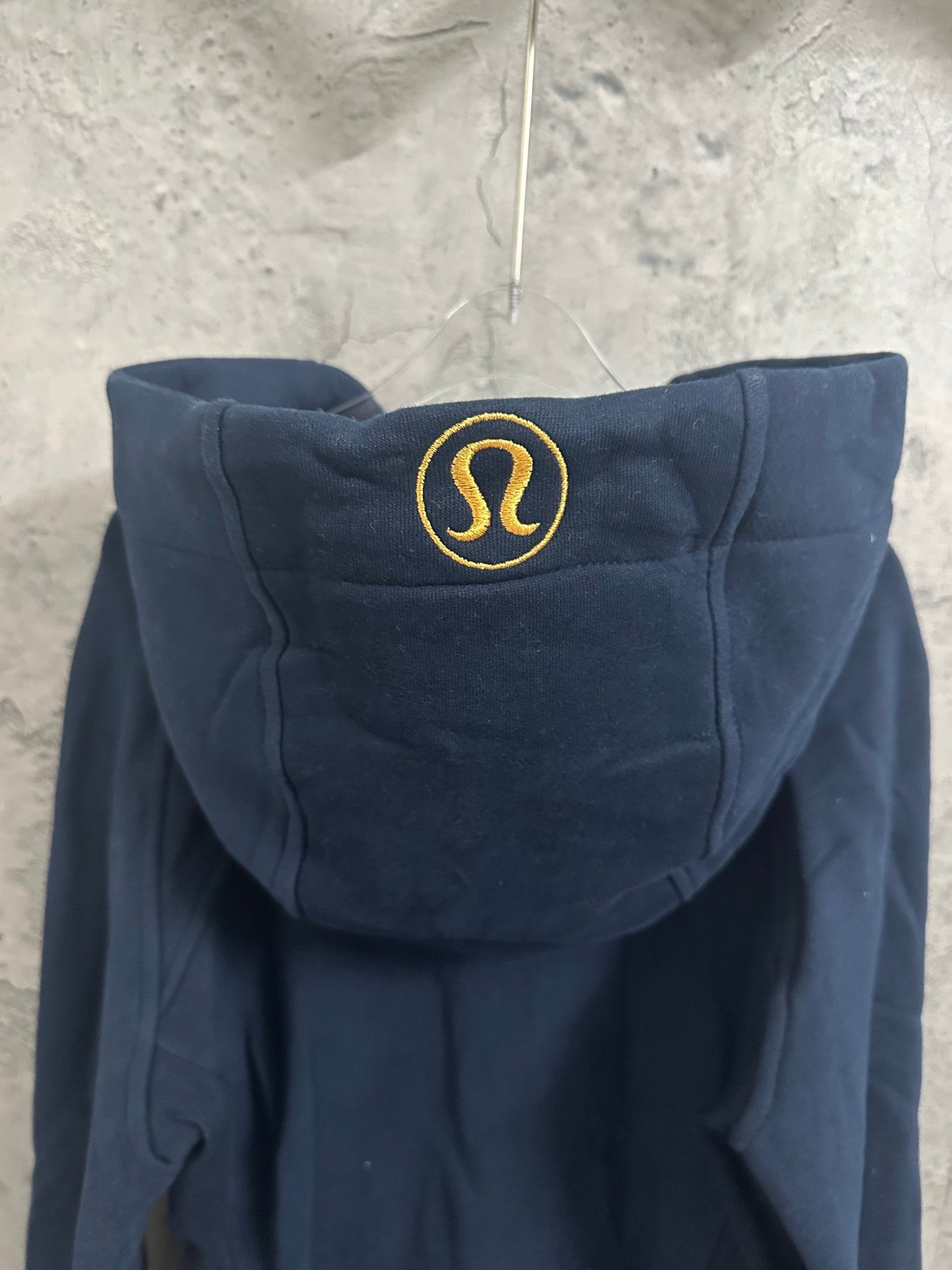 Dark navy hoodie with hood up and embroidered round logo at the back