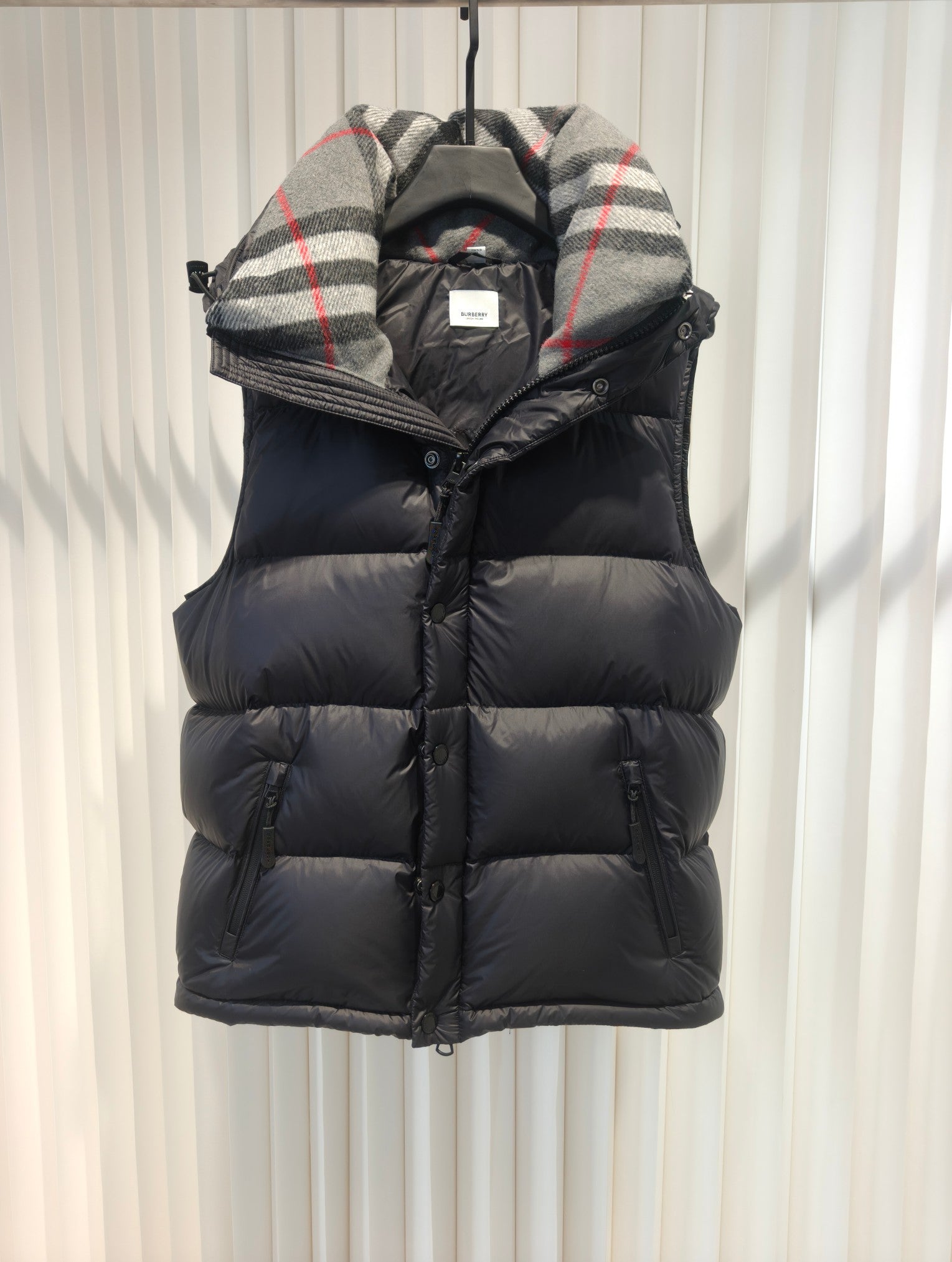 Sleeveless-style puffer vest with plaid hood lining and dark padded front panel