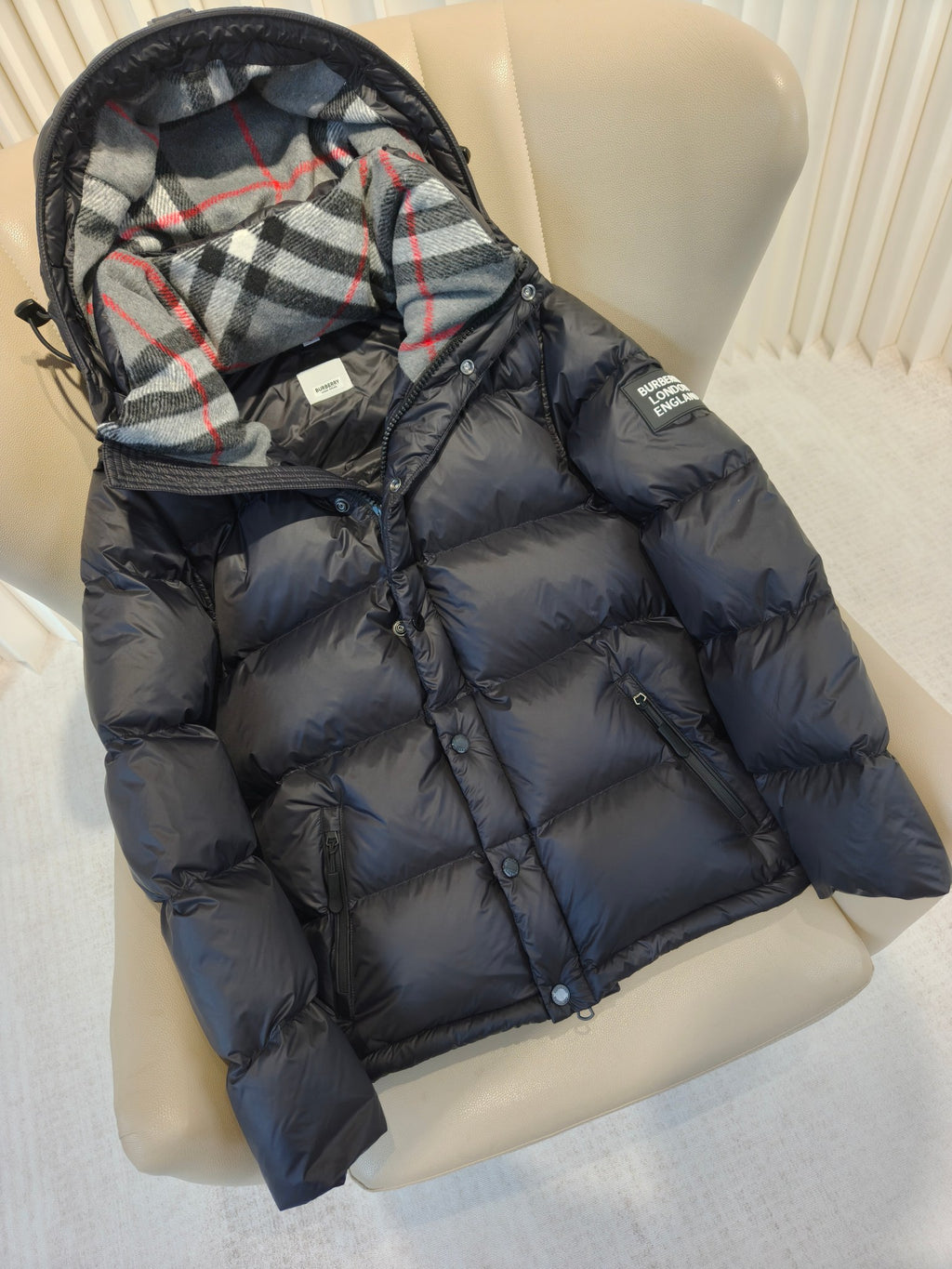 Puffer jacket angled close-up, plaid hood lining, dark padded sleeves and zip-front