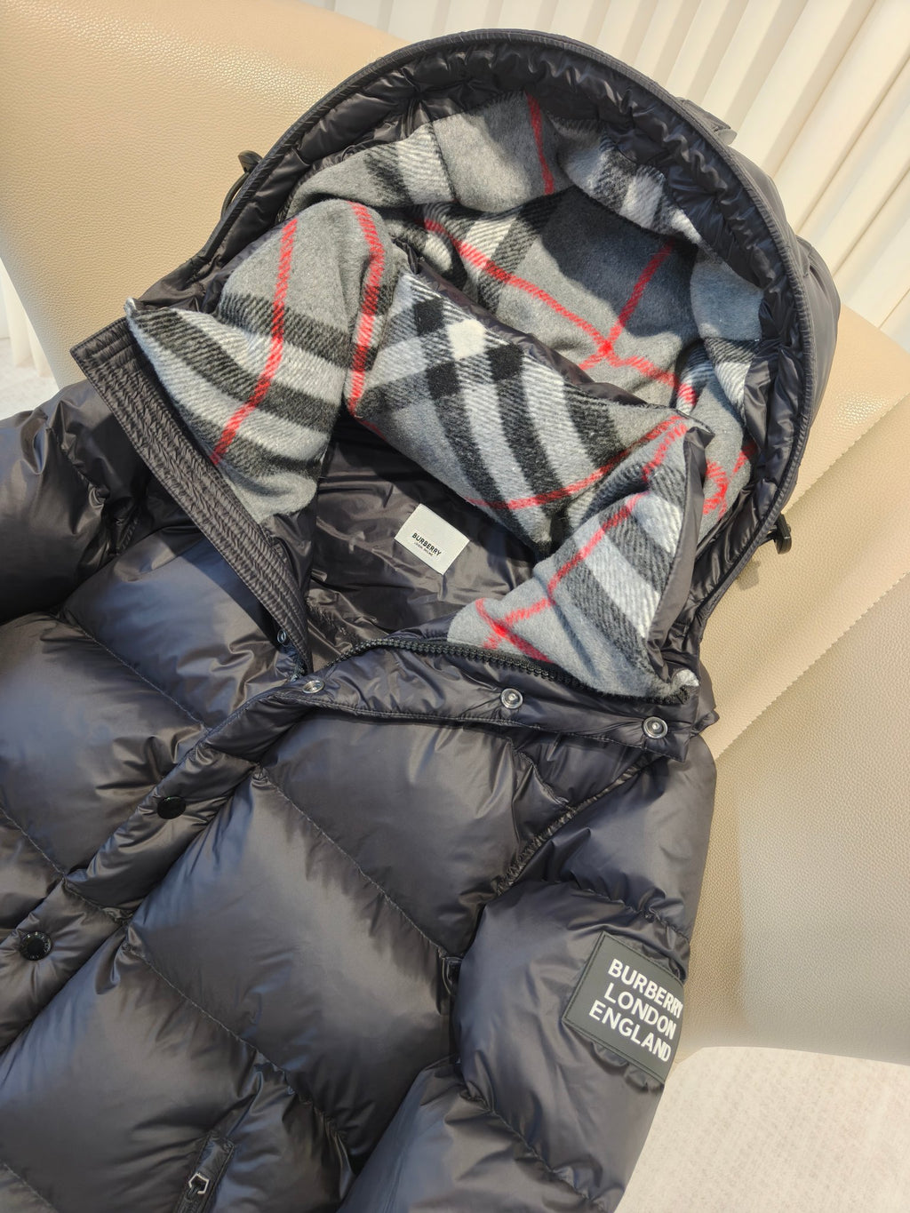 Puffer jacket hood lining close-up with plaid pattern and dark exterior front