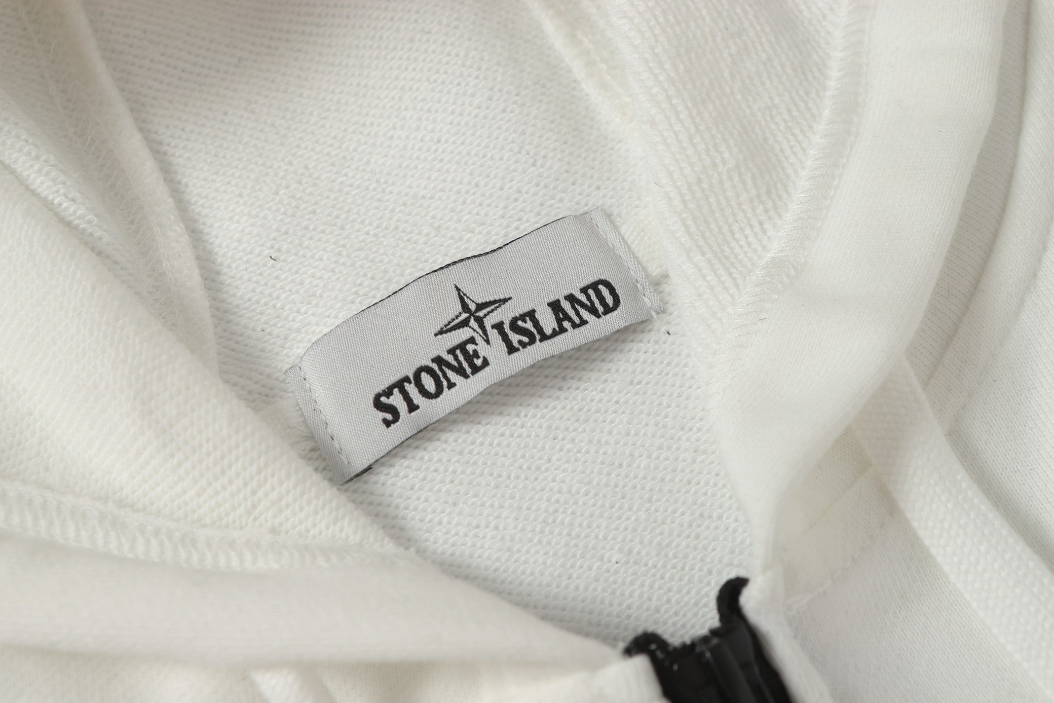 White jacket fabric with Stone Island neck label and black zipper pull