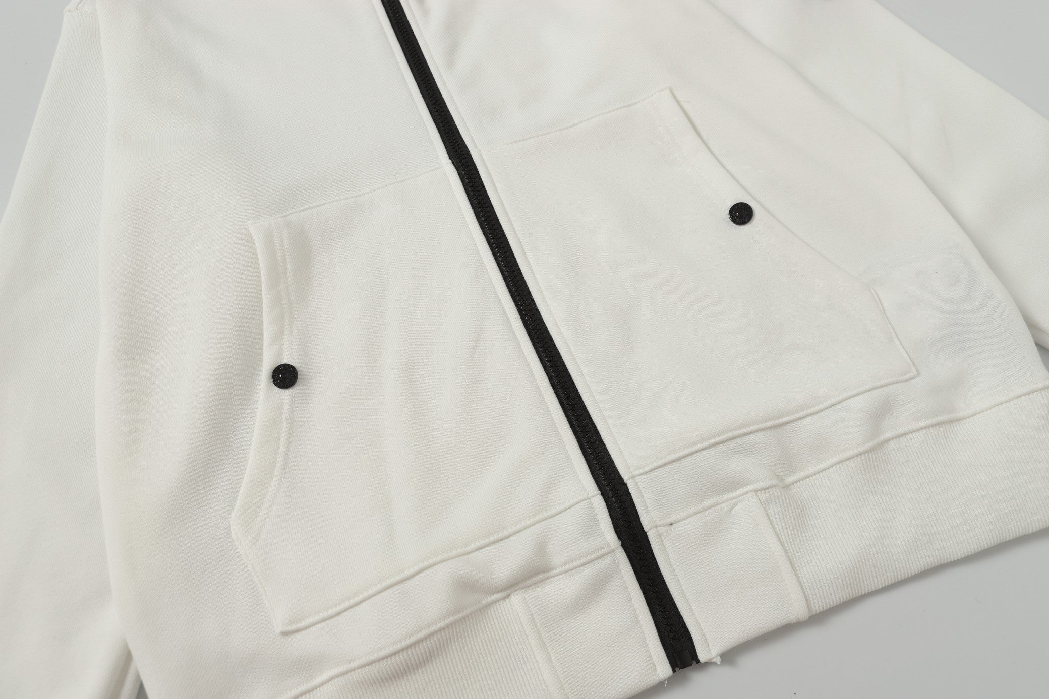 White hooded jacket showing two front flap pockets and black zipper