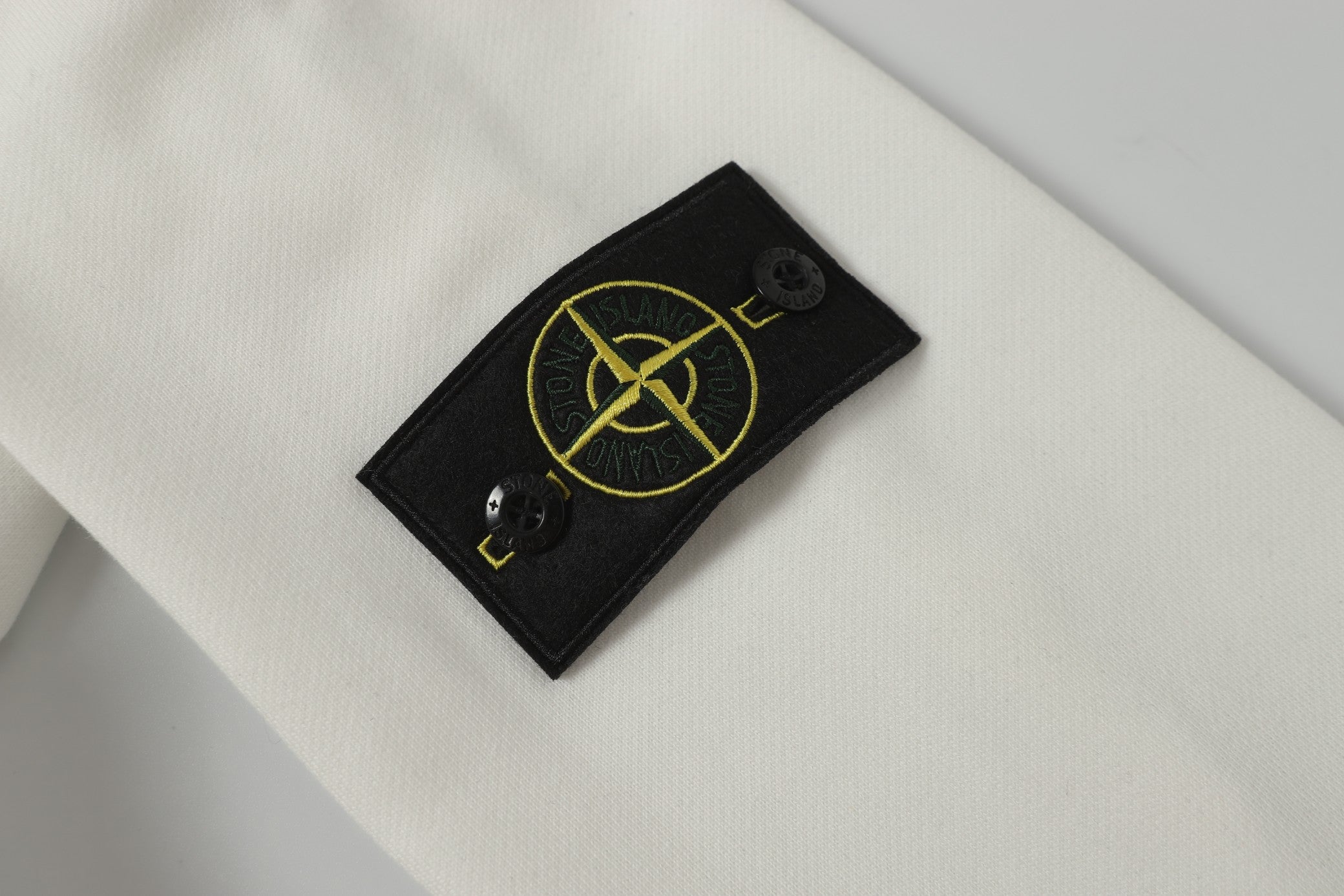Stone Island logo patch on white hooded jacket front near neckline