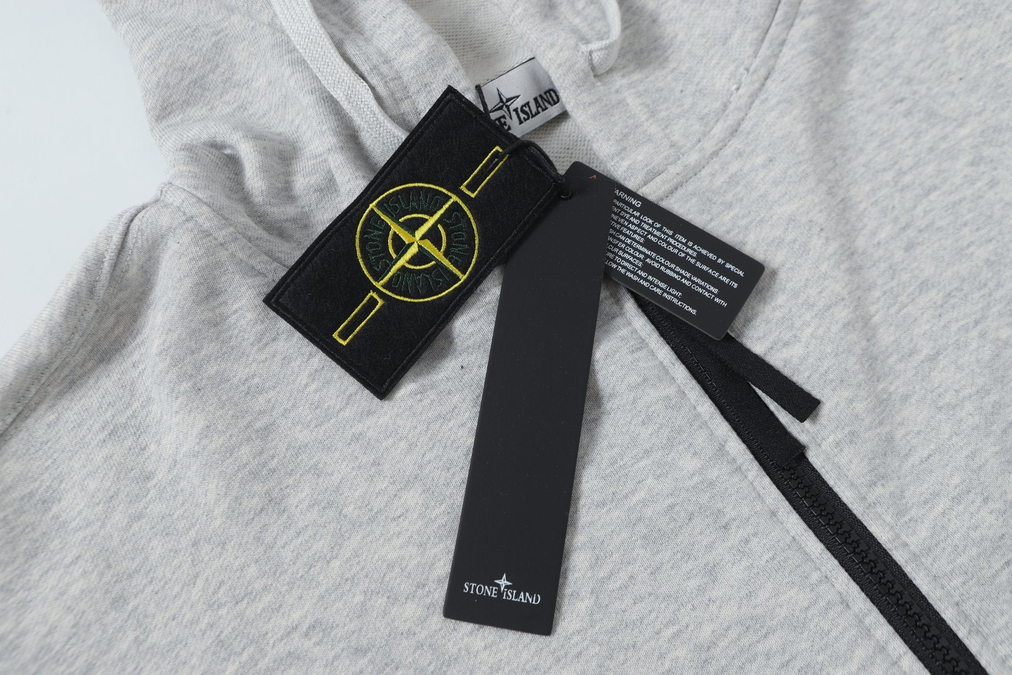 Light gray hoodie neckline with inner label and black zip pull tag