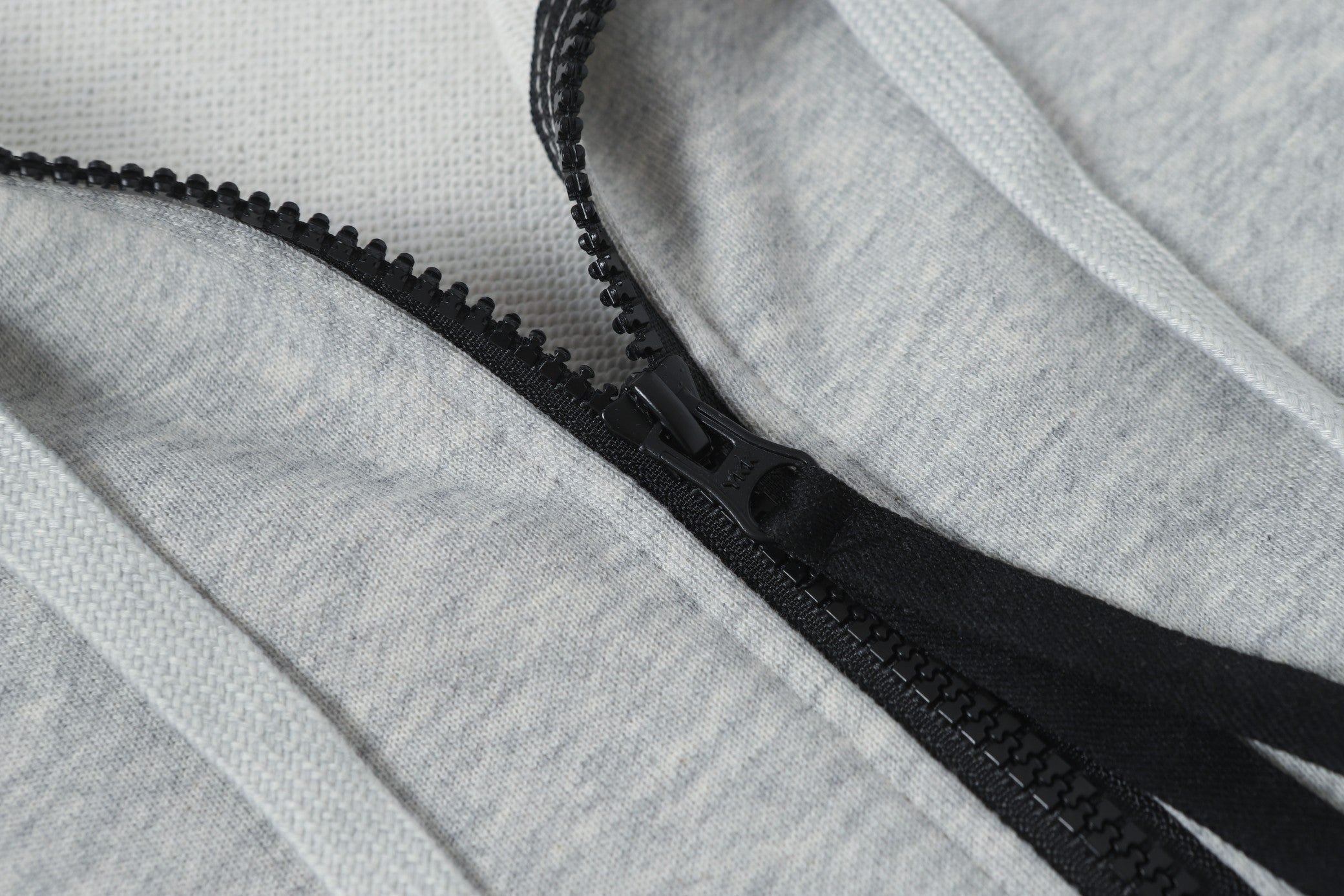 Black zipper detail on light gray hoodie placket with stitched edges