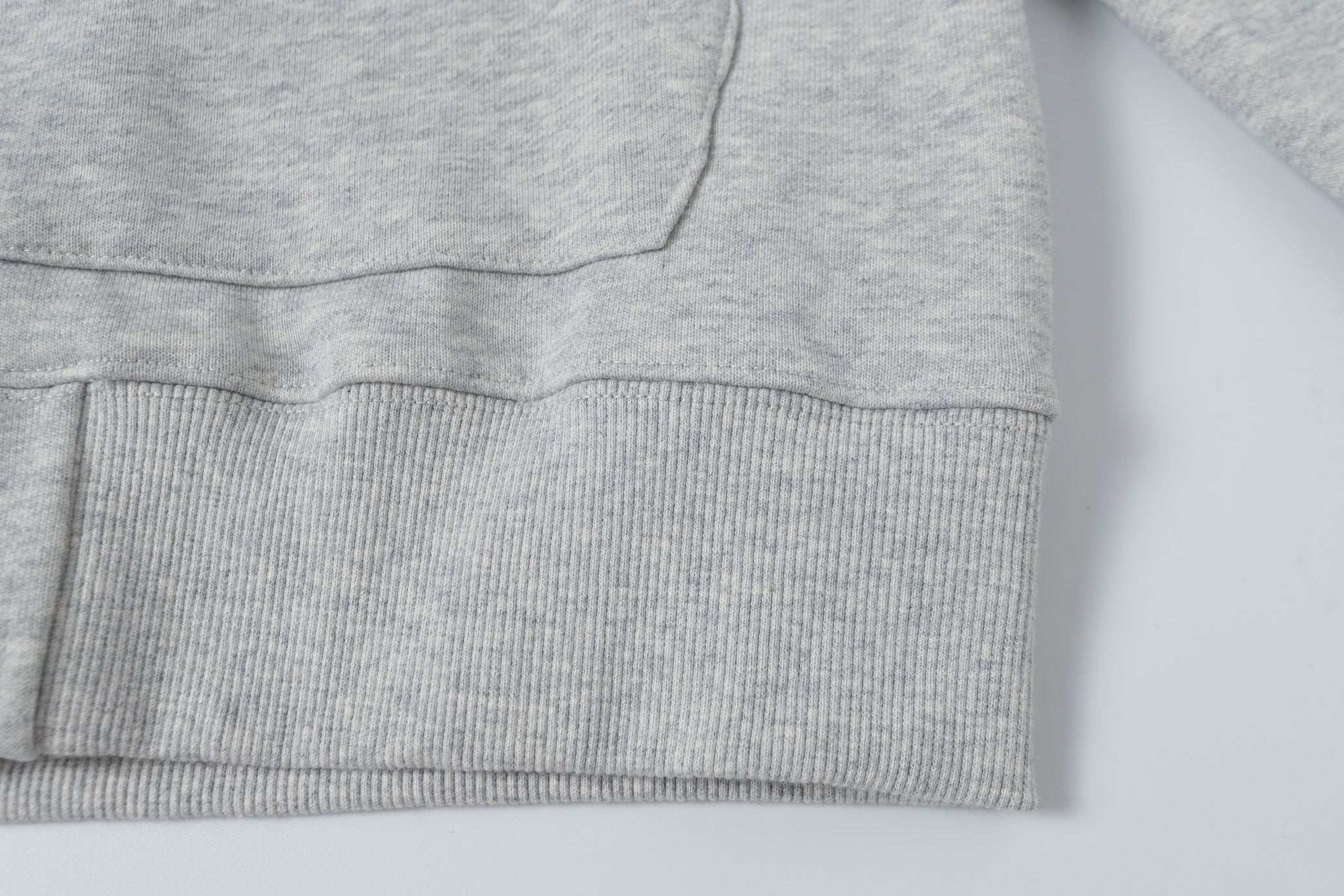 Light gray hoodie hem with ribbed knit cuff and stitched lower edge