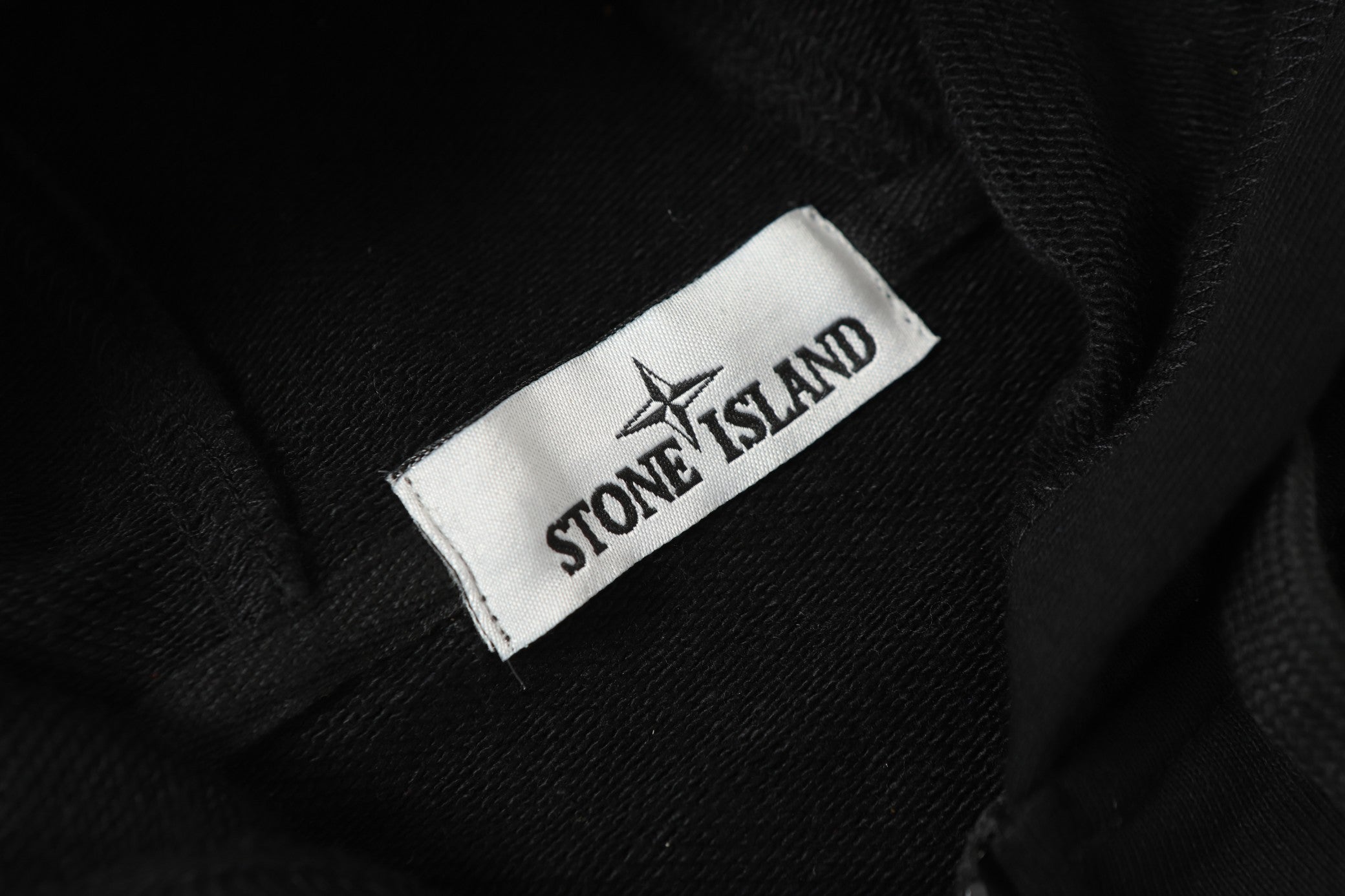Stone Island woven neck label on black jacket fabric