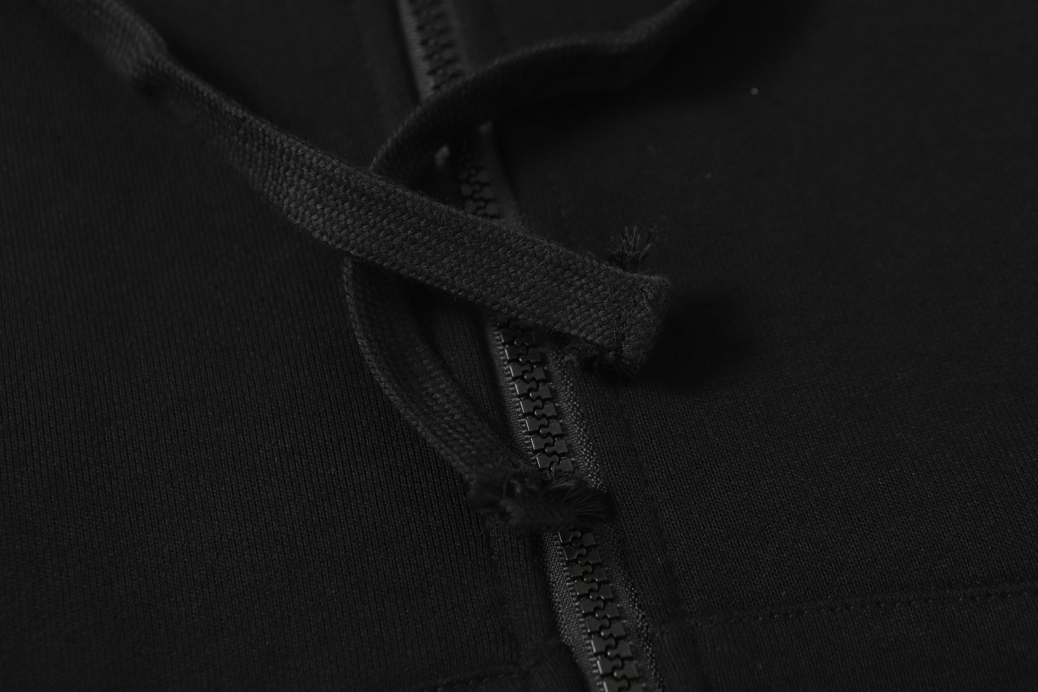 Black hooded jacket zipper and drawstring close-up