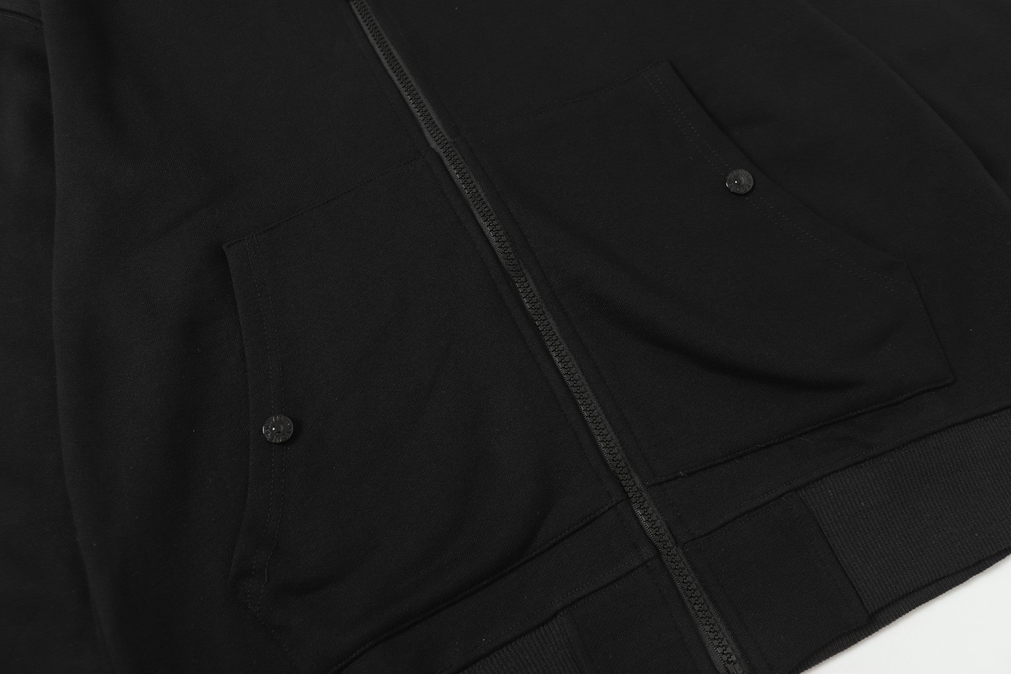 Black zip-up hooded jacket front pocket and zipper seam