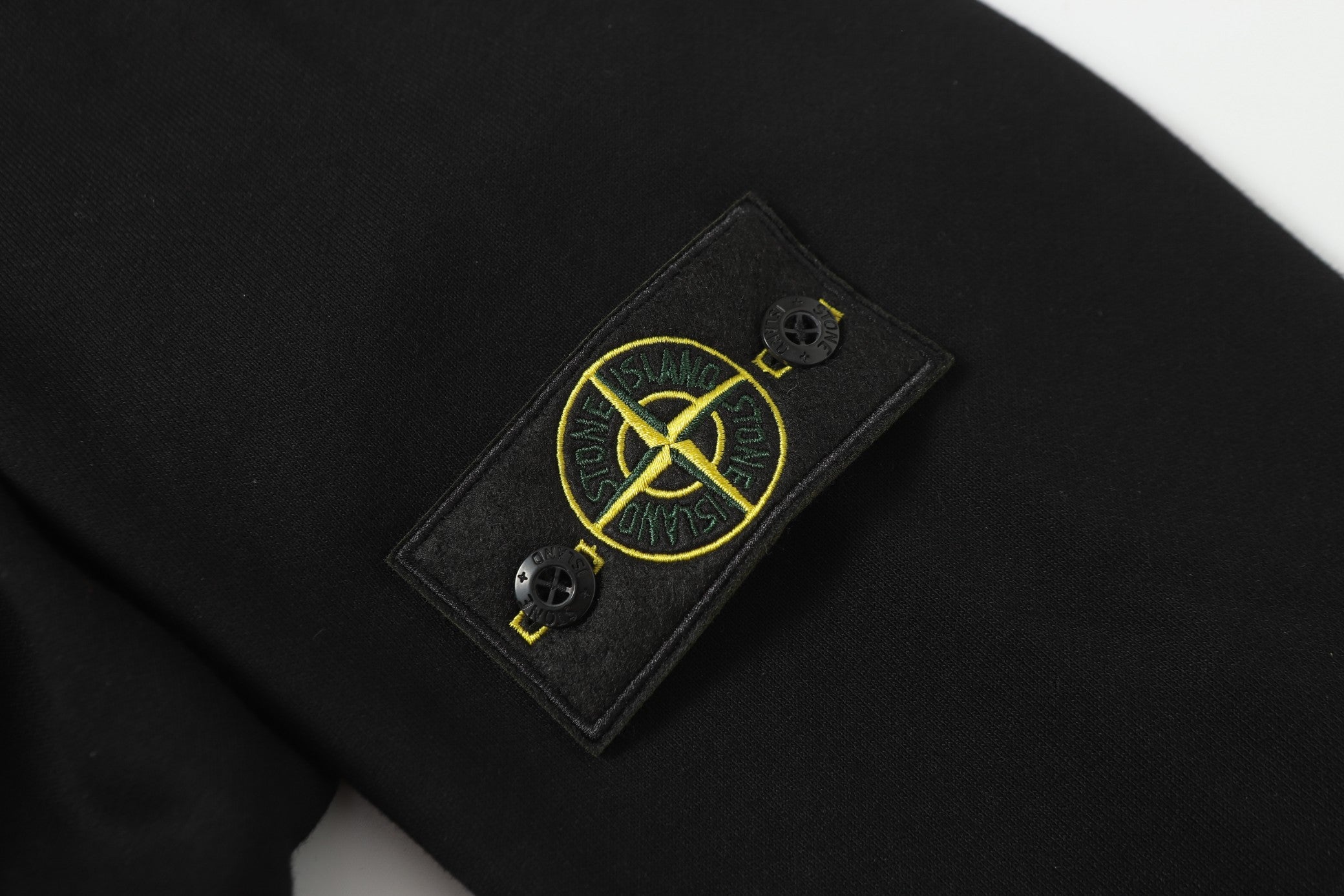 Dark garment with Stone Island logo patch on chest