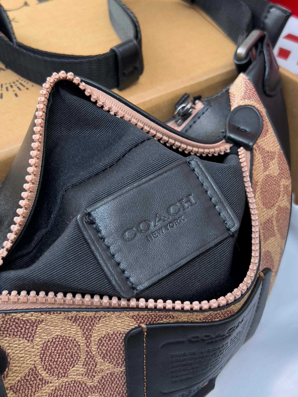 Coah belt bag close-up of black logo patch and rose-gold zipper