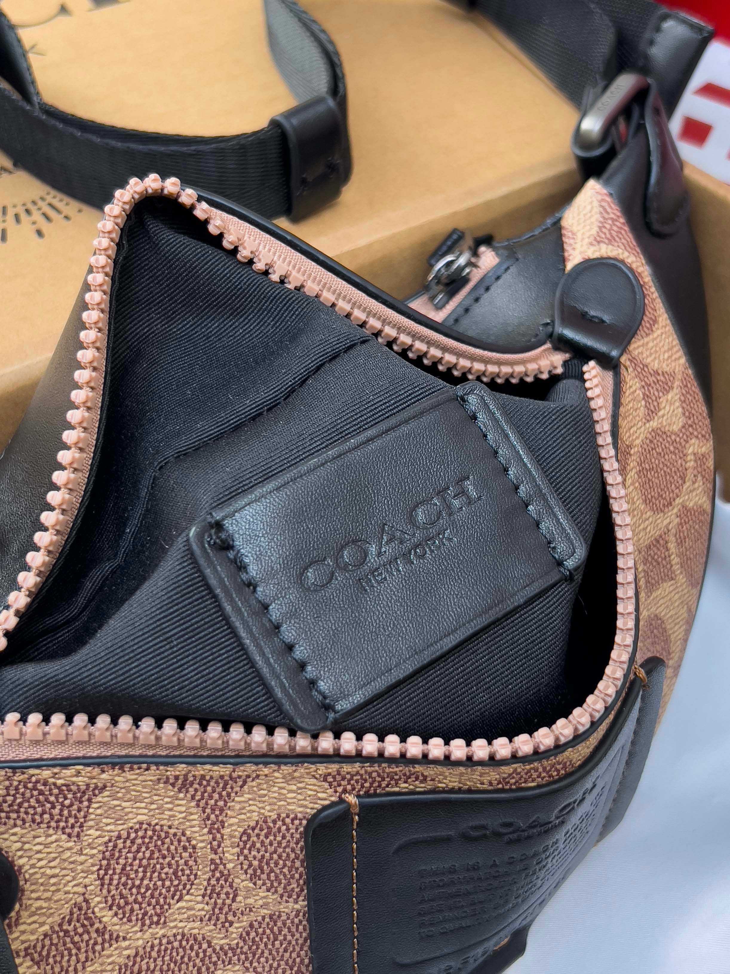 Coah belt bag close-up of black logo patch and rose-gold zipper