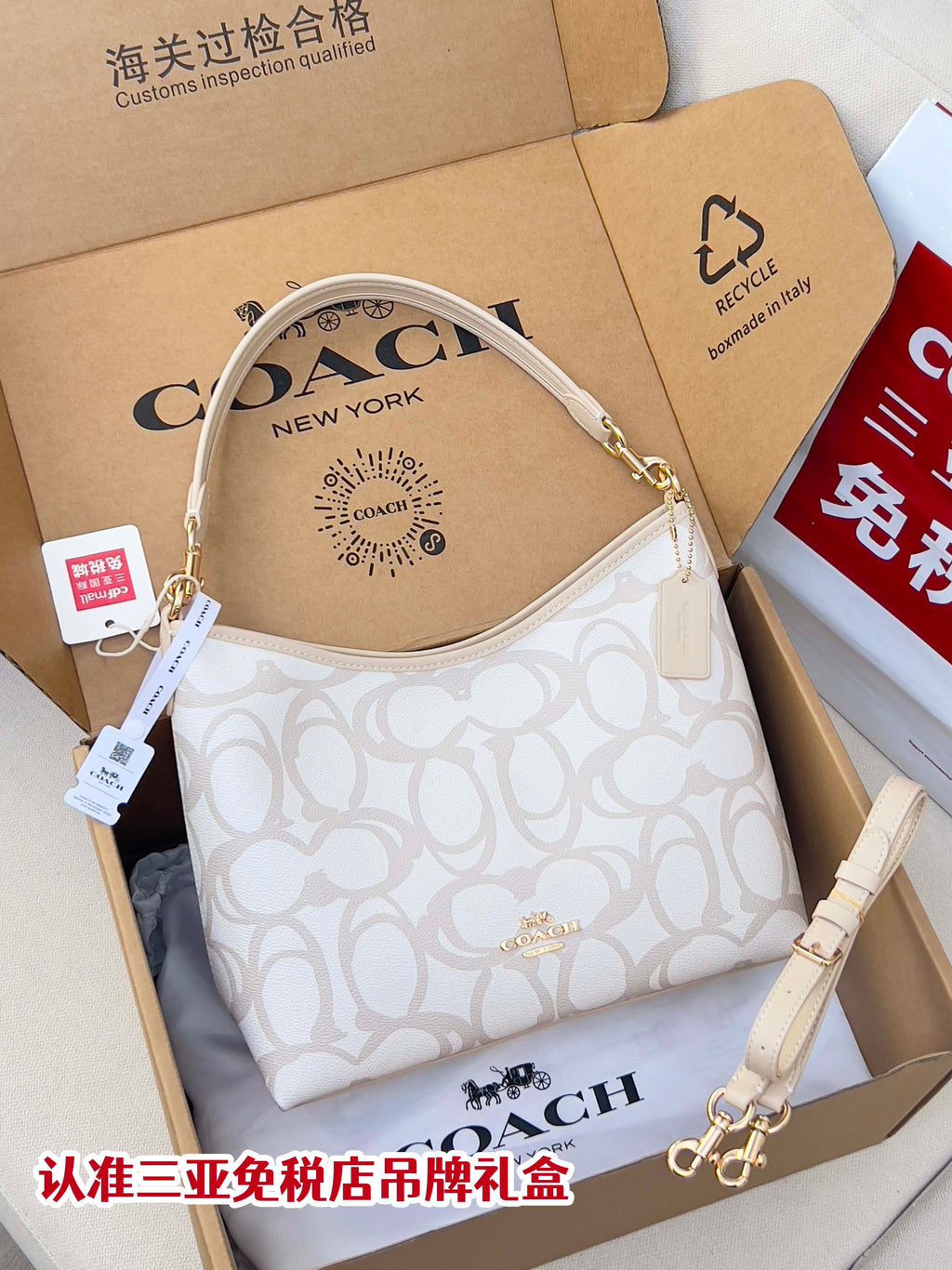 White patterned Coach hobo bag with top handle and shoulder strap, gold hardware.
