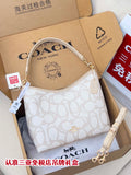 White patterned Coach hobo bag with top handle and shoulder strap, gold hardware.