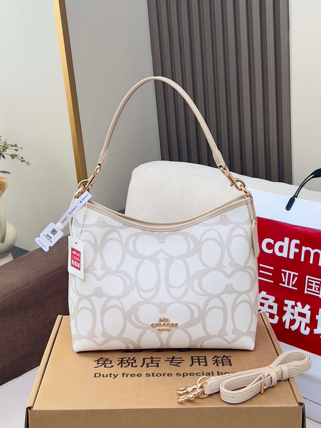 White Coach hobo bag with tan trim, top handle, and adjustable shoulder strap.