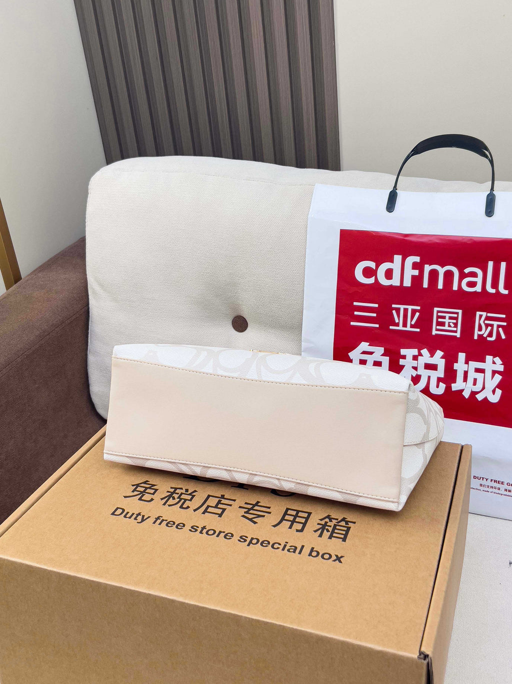 White Coach small pouch with handle and shoulder strap, placed on cardboard box.