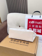 White Coach small pouch with handle and shoulder strap, placed on cardboard box.