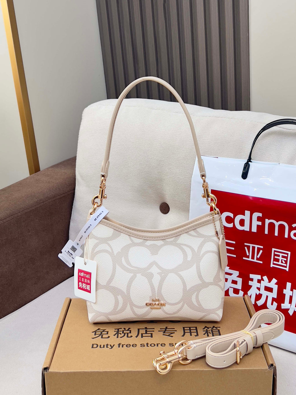 Coah crossbody bag with beige top handle strap, white logo fabric, gold hardware