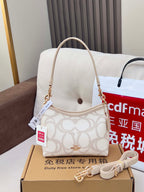 Coah crossbody bag with beige top handle strap, white logo fabric, gold hardware