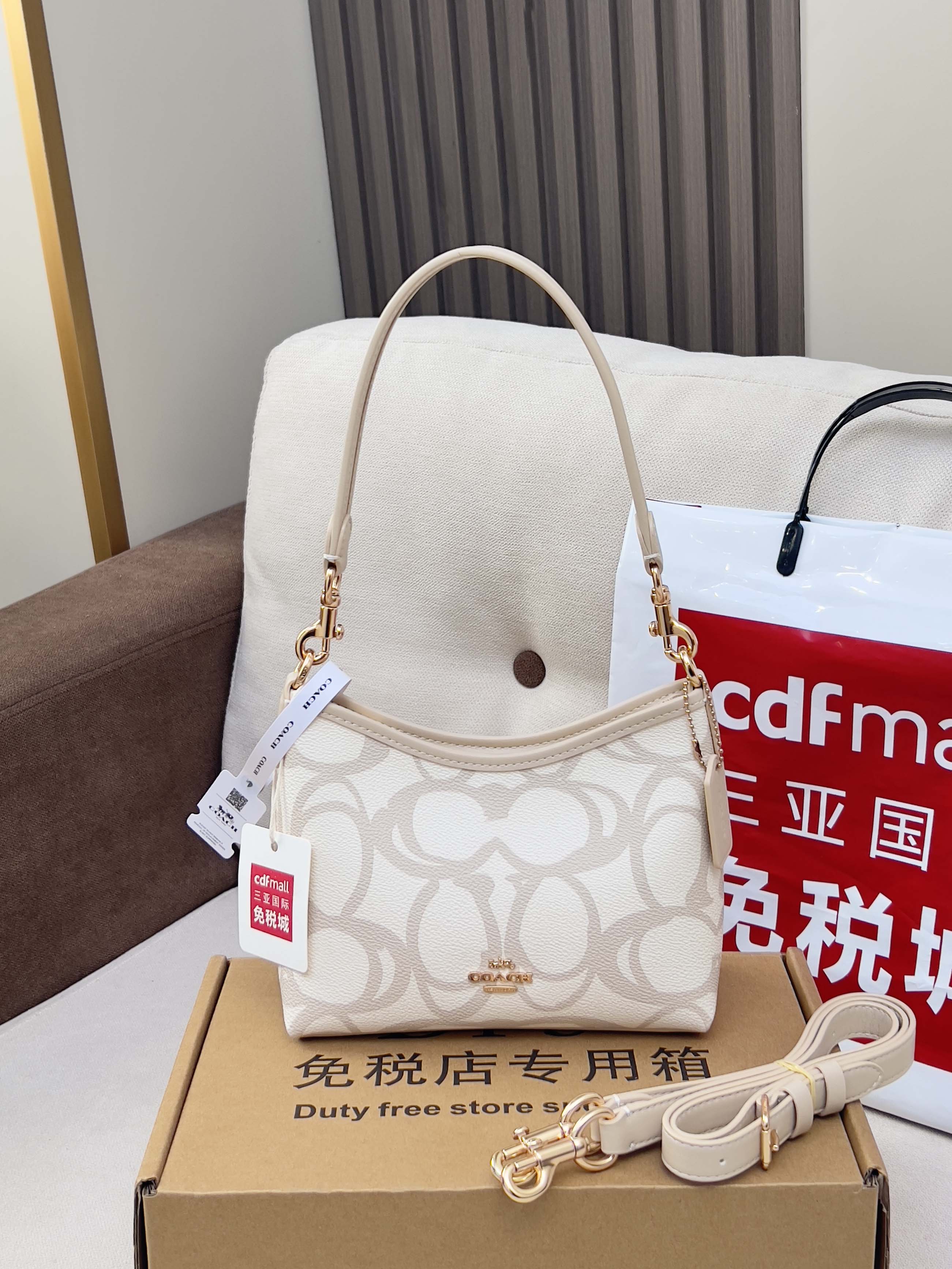 Coah crossbody bag with beige top handle strap, white logo fabric, gold hardware
