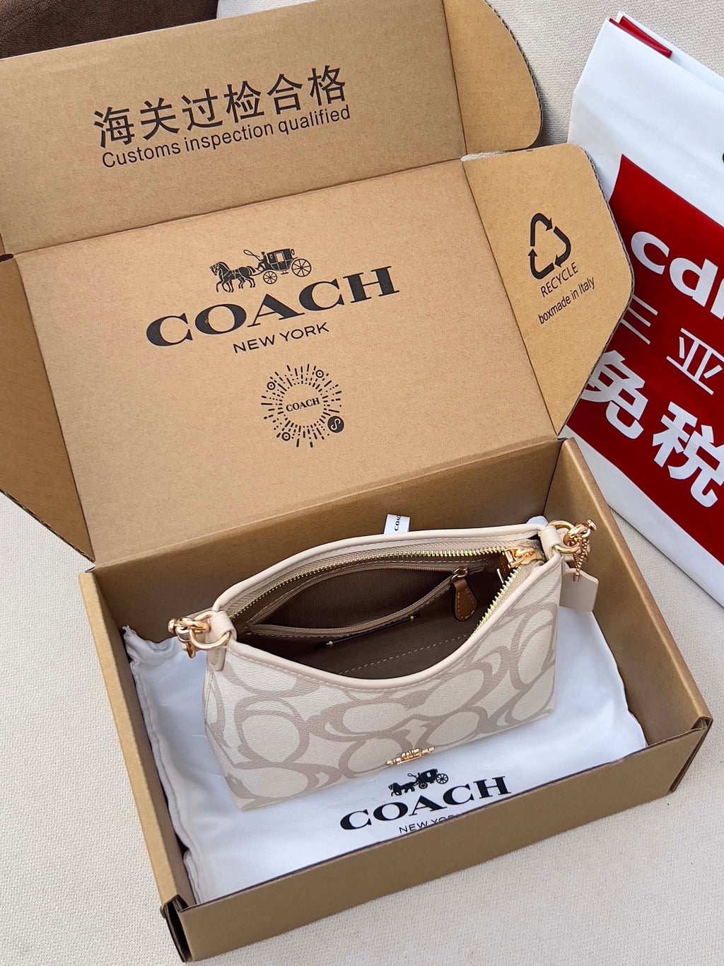 Coah shoulder bag with white logo canvas inside a branded box with tissue padding