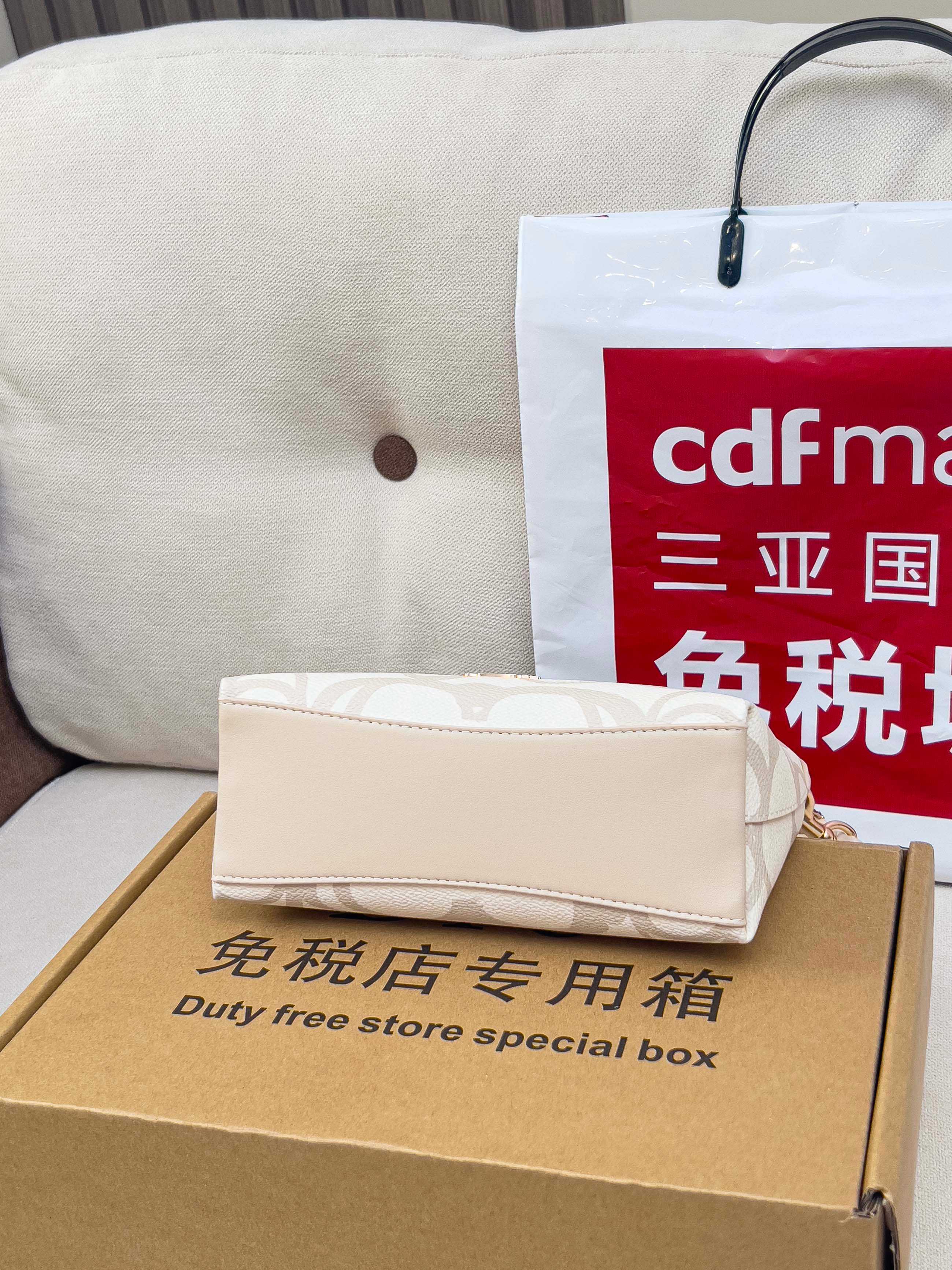 Coah bag gift box with beige pouch and retail shopping bag beside it