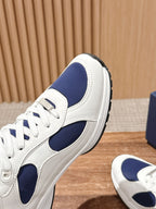 Side view of white and navy unisex leather sneakers with lace-up closure