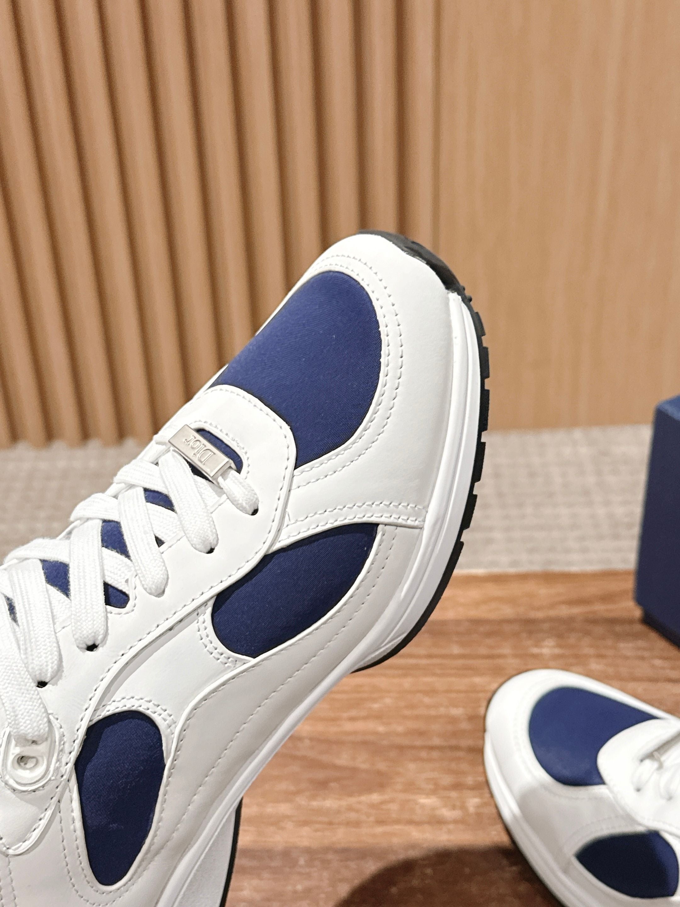 Side view of white and navy unisex leather sneakers with lace-up closure