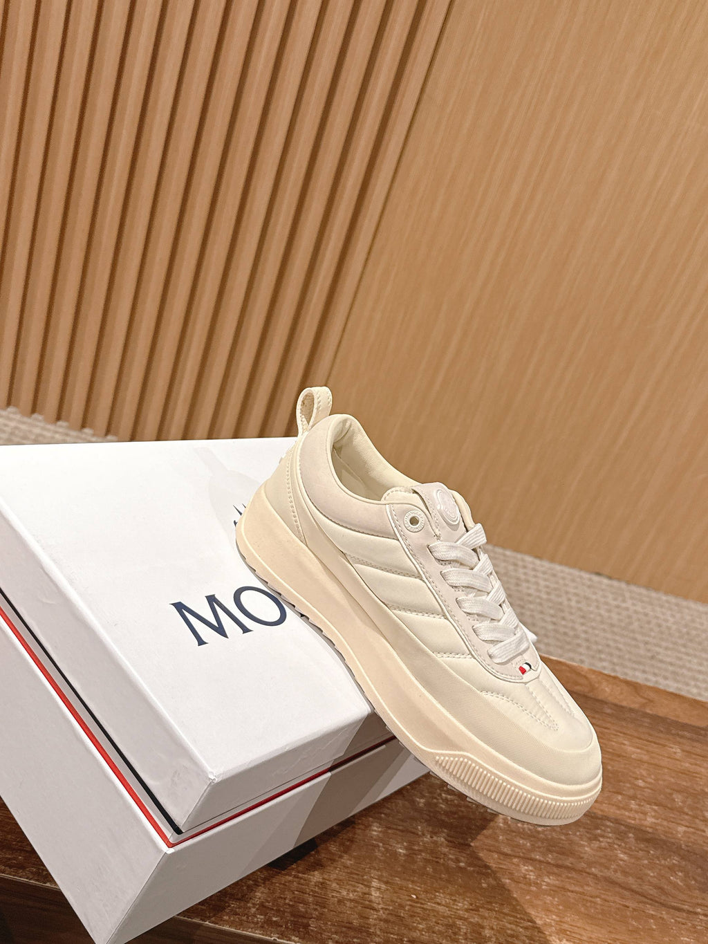 Moncler luxury shoes in cream, angled side view with laces and cushioned sole.