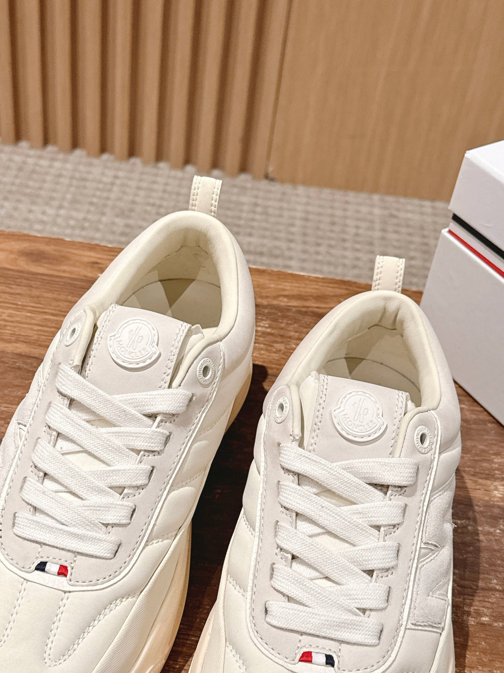 Moncler luxury shoes in cream, close-up front views with lace-up and embossed patch.